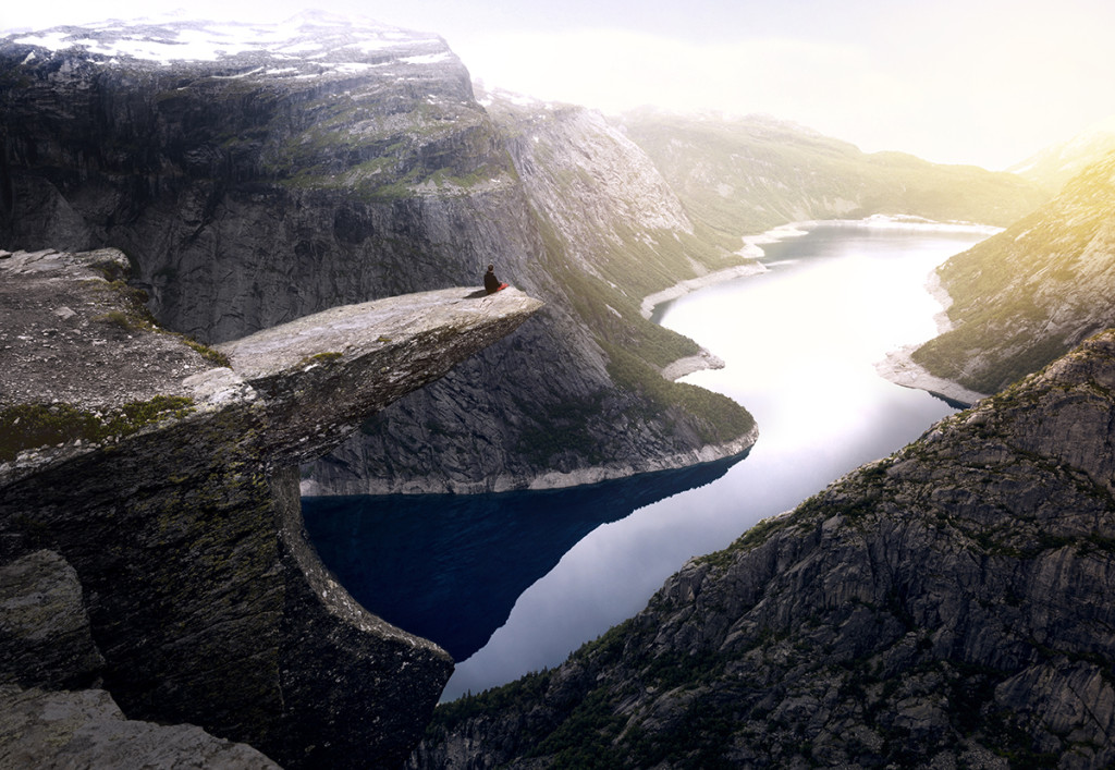 Lonely character sitting at the edge of the trolltunga cliff during the sunset
